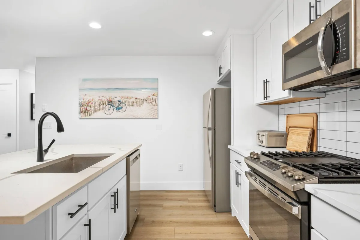 A spacious kitchen with a central island, stainless steel appliances, and colorful artwork. This area offers plenty of space for group activities, food prep, or informal meetings, blending functionality with a contemporary vibe.