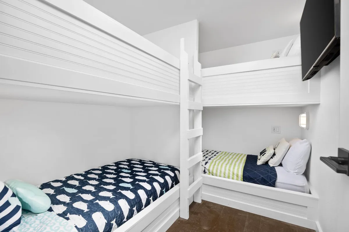 A cheerful bunk room with four colorful built-in bunk beds, decorated with playful bedding and decorative pillows. The space is vibrant and inviting, perfect for kids, cousins, or groups seeking a fun, shared sleeping area.